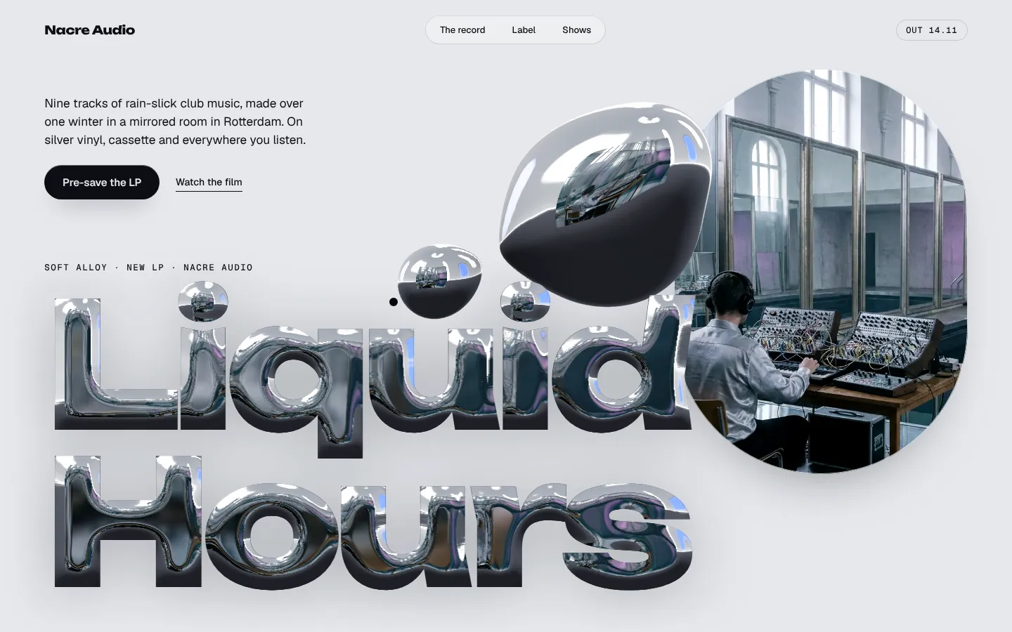 Bubble letters in liquid chrome, reflecting a room, beside a round glass window.